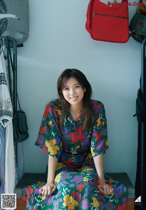 A woman sitting on a window sill next to a window.