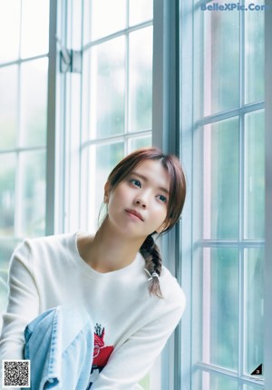 A young woman looking at the camera with her hand on her chin.