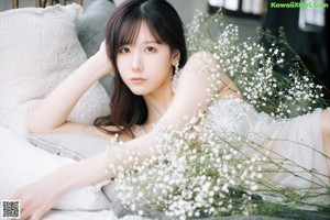 A woman in a white dress holding a bunch of flowers.