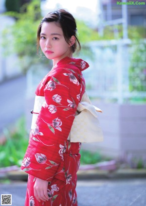 A woman in a kimono and a straw hat posing for a picture.