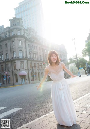 A woman in a white dress standing on the street.