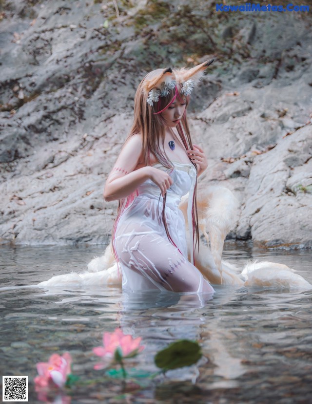 A woman in a white dress is standing in the water.